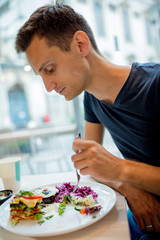 Young man eating salad in a cafe