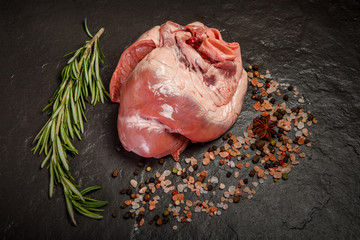 top view closeup raw cow heart with spices and rosemary