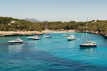 Fototapeta na wymiar Yatchs in urquoise water in Cala Mondrago view from the sea, Mondrago Natural Park, Majorca.