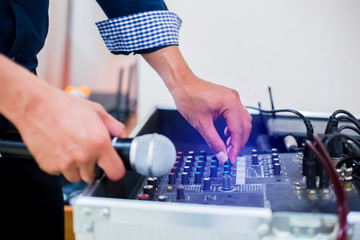 Microphone in hand and adjust an audio mixer controller in the control room, Sound mixer control...