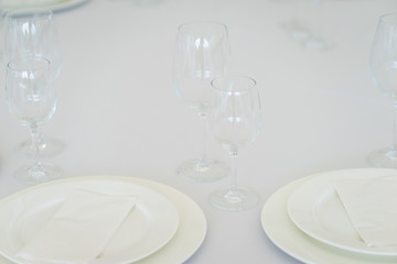 Clean empty glasses and plates on the table in the restaurant prepared for guests. 