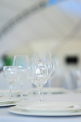 Clean empty glasses and plates on the table in the restaurant prepared for guests. 