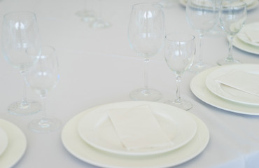 Clean empty glasses and plates on the table in the restaurant prepared for guests. 