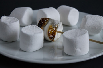 Fototapeta na wymiar White marshmallow on a stick burnt by fire caramelized
