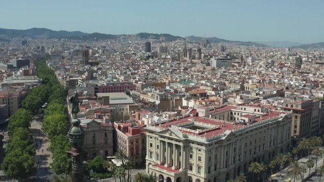 Aerial view of famous Square of Gate of Peace with Columbus monument in Barcelona historic center on background of scenic cityscape. Drone shot of Barcelona urban buildings with mountains in distance