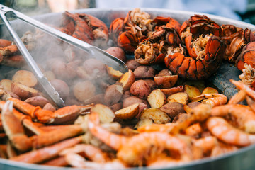 Large pot pan of grilled seafood at a county fair festival. This includes lobsters, shrimp and crab