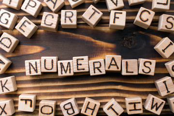 word numerals composed of wooden cubes with letters,  symbol that represents a number concept scattered around the cubes random letters, top view on wooden background