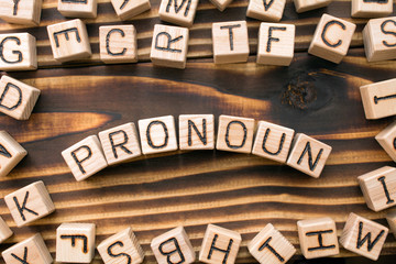 Obraz premium word pronoun composed of wooden cubes with letters, Part of speech concept scattered around the cubes random letters, top view on wooden background