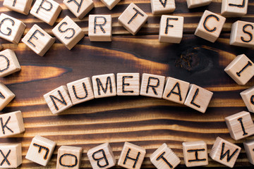 word numeral composed of wooden cubes with letters,  symbol that represents a number concept scattered around the cubes random letters, top view on wooden background