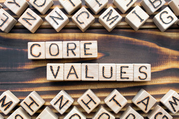 core values - phrase from wooden blocks with letters, meaningful statements concept, random letters around, top view on wooden background