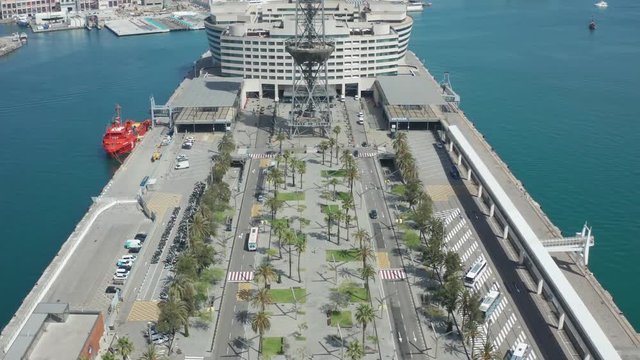 Aerial view of Barcelona port Vell with cable car tower connecting old port and mountain Montjuic. Drone flight over industrial harbour on background of aerial tramway and beautiful seascape