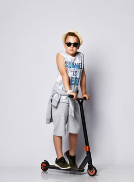 teen boy posing in studio with scooter scooter on a light background in summer clothes