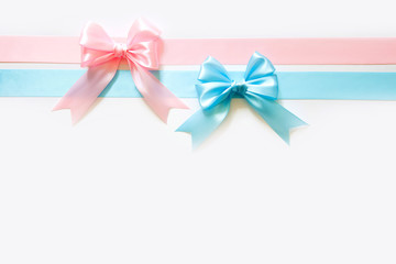 Blue and pink wide satin ribbon with a bow. White background. Birth of a boy or girl.