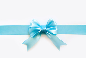 Blue wide satin ribbon with a bow. White background.