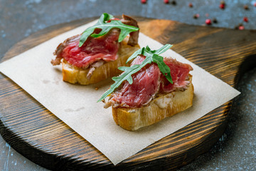 Bruschetta with roast beef on blue concrete table