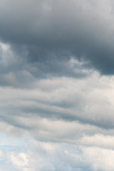 Stormy sky with clouds in various shades of grey with a hint of blue sky