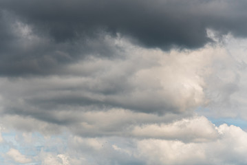 Stormy sky with clouds in various shades of grey with a hint of blue sky
