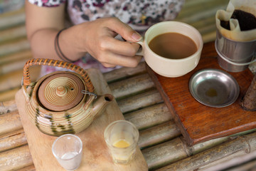 Happy asian woman holding a cup of drip coffee on wooden table,Enjoying morning coffee concept.