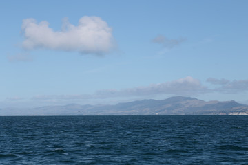 Delightful sea landscape with blue surface of the water, magic feather clouds on the sky over mountain in Kaikoura,New Zealand