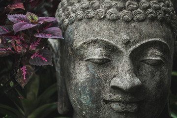 Stone Buddha face close-up. Handmade carved Buddha statue in balinese garden as decoration.