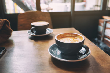 Closeup image of two blue cups of hot latte coffee on wooden table in cafe