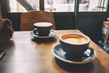 Closeup image of two blue cups of hot latte coffee on wooden table in cafe
