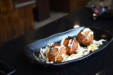 Three takoyaki sweets placed in a black plate. Japan food.
