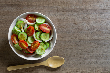 top view of vegetables salad in a bowl on wooden table. homemade style healthy food concept.