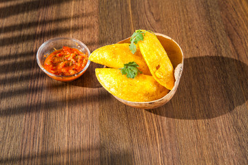 Colombian empanada with spicy sauce on wooden background