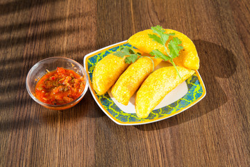 Colombian empanada with spicy sauce on wooden background
