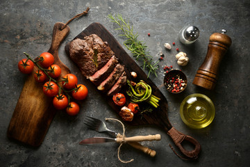 Meat steak serving on wooden butcher board with various ingredients surrounding,with fork and...