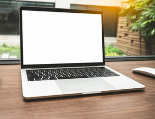 Fototapeta premium Empty white screen laptop computer on wooden table top, business concept. Mockup design with copy space.