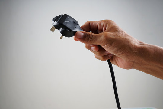 Malay hand in cropped holding the cable plug with copy space.            