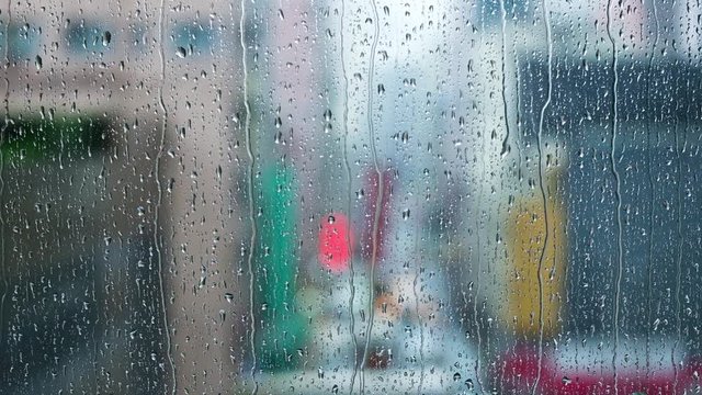 Rain droplets on window and colorful traffic bokeh light.