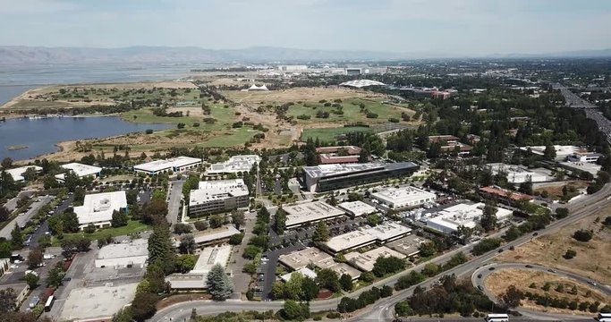 Aerial birds eye view of corporate tech offices Fly forward Google campus shoreline amphitheater lake