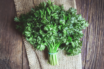 bunch of parsley on burlap on a wooden table.