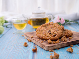 Tasty chocolate chip cookies stacked on a board served with tea and teapot on blue wooden table.Organic homemade snacks for healthy breakfast.Space for text and copy space