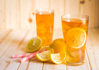 Glasses of ice tea with lemon slices on wooden background