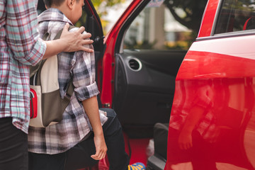 Close up hand of asian mother or parent helping son or pupil to getting in the red car to ride to...