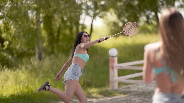 Happy women in bikinis playing badminton at a resort, medium shoulder shot