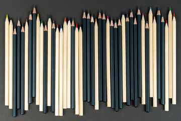 Set black and white pencils on black paper background. Mock up, copy space. concept tolerance of white and black people living next door.