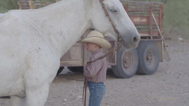 Young Rancher Boy Holding Reins of Powerful White Stallion.