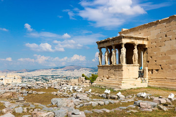 Fototapeta premium Ruins of famous ancient greek temple Erechtheion, on the north side of the sacred rock of the Acropolis of Athens with statues of Caryatids under blue sky with clouds