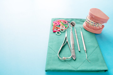 Dentist tools and orthodontic model on blue background.