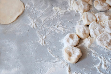 Products from flour, the cooking process. Cutting dough on a white table, sprinkled with flour. Cut into pieces the finished dough.