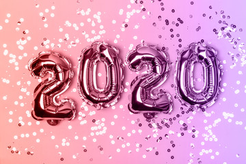 Numbers 2020 made from foil balloons on neon lights background and sparkles. Christmas concept