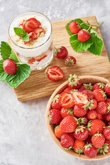 Strawberry granola or smoothie in a glass and fresh berries in wooden bowl, top view. Healthy breakfast