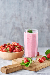 Strawberry milk shake in a glass jar and fresh strawberries with leaves