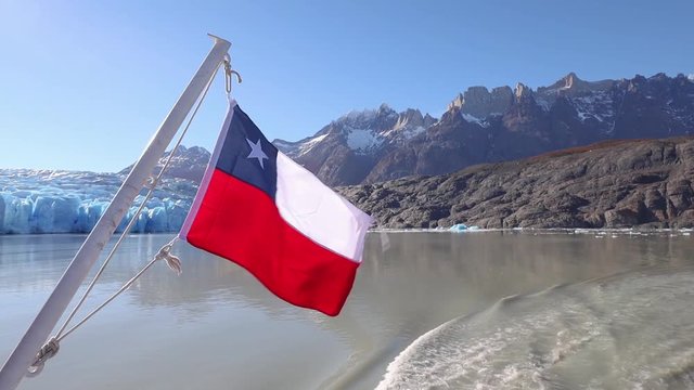 Chilean flag waving in the wind over glaciar grey at Torres del Paine National Park