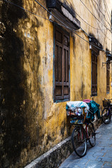 Vintage Bicycle by a yellow ancient wall of an old building in the Ancient City of Hoi An, Vietnam.Vertical, portrait view.